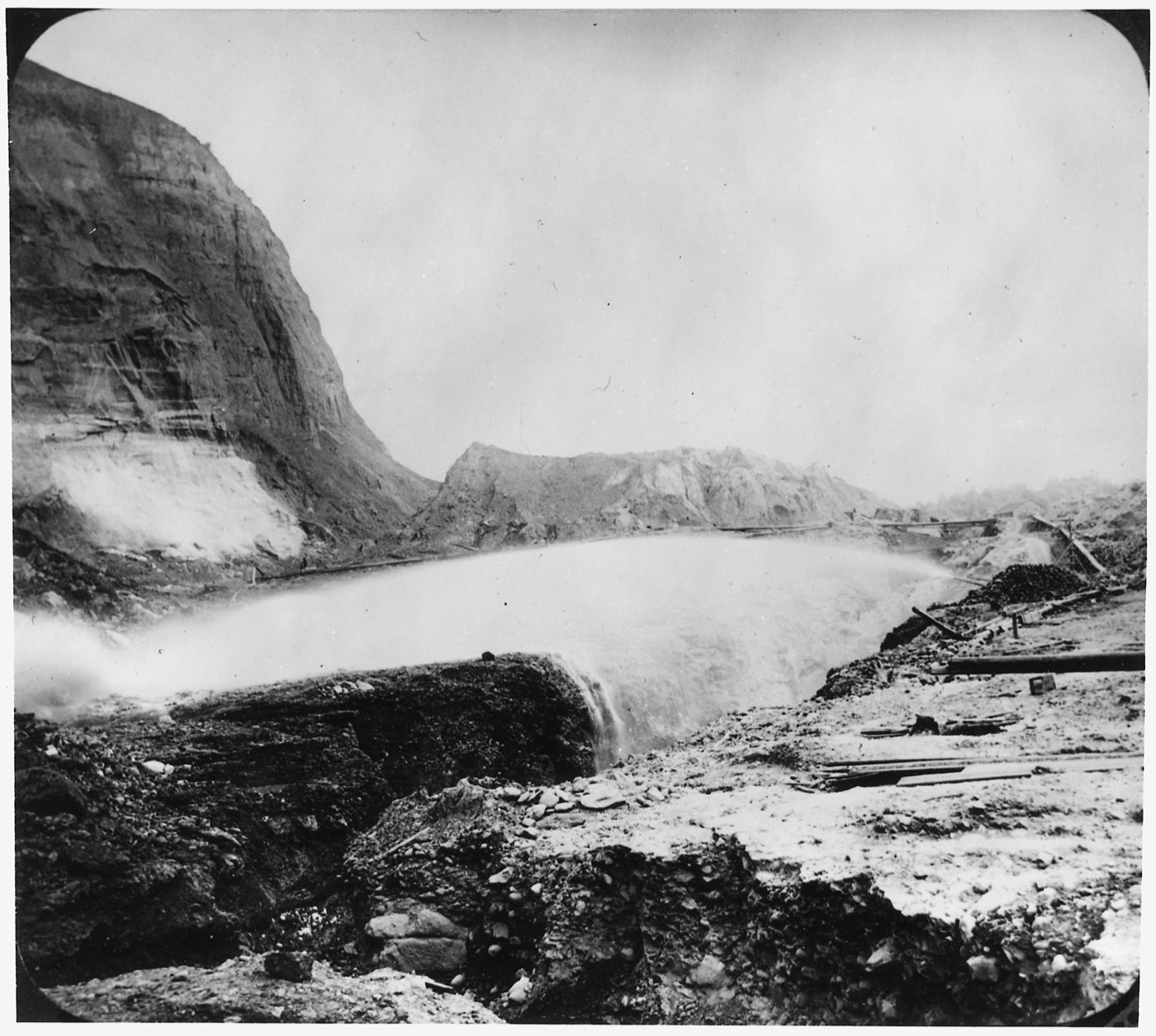A nineteenth-century hydraulic mining operation: a high-pressure iron water cannon blasting a denuded hillside into slurry to wash out the gold.