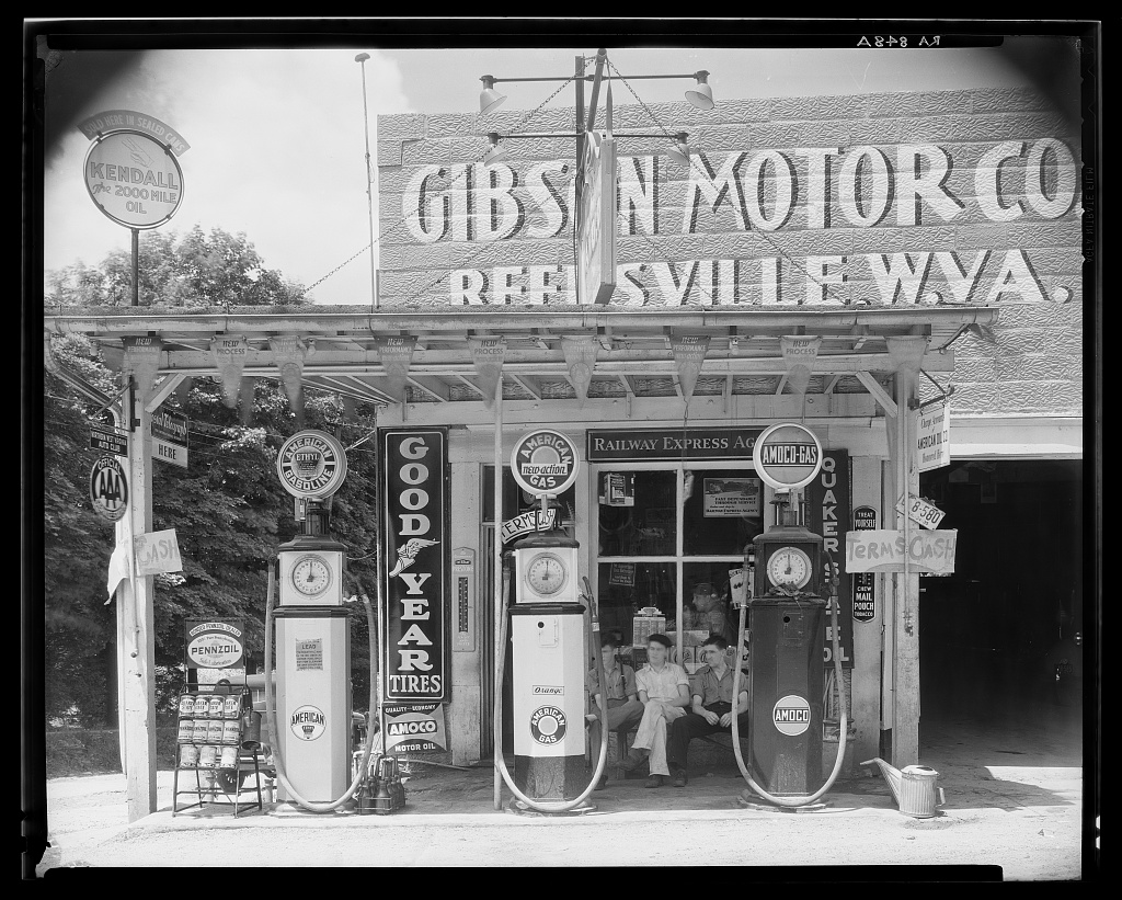 A clapboard gas station with a single attendant standing beside two pumps on a dirt road in West Virginia, photographed by Walker Evans in June 1935.
