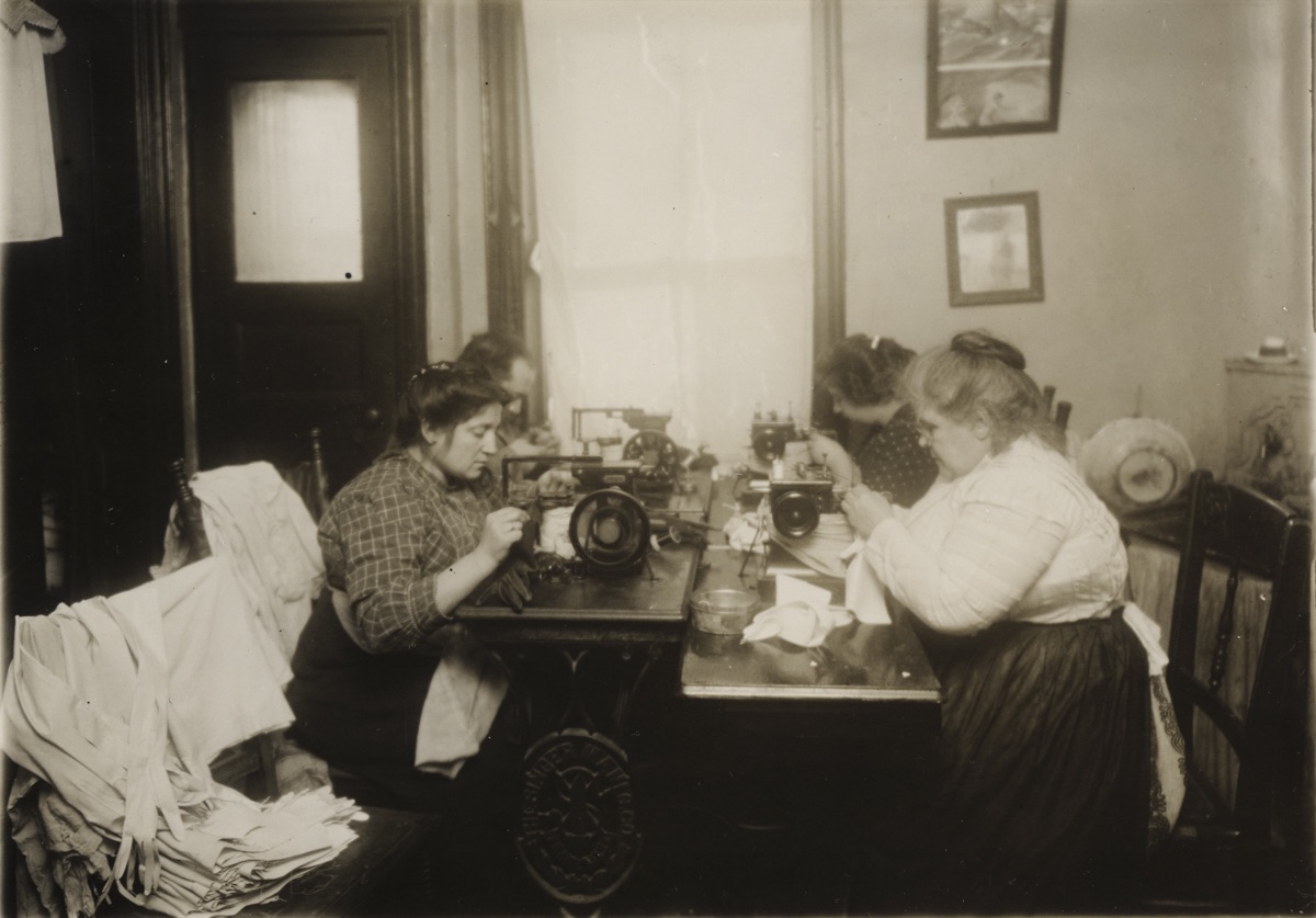 A worker dwarfed by a wall of industrial valves and piping in an early-20th-century power plant.